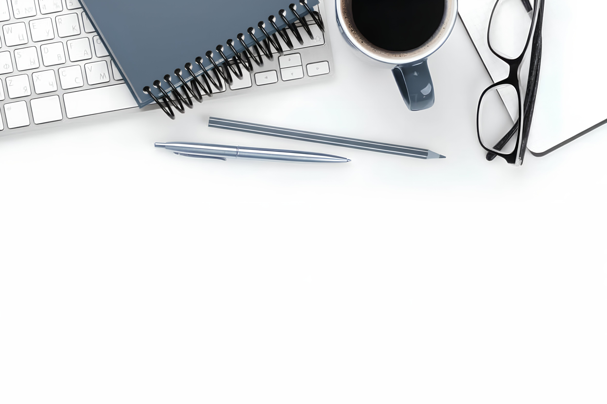 Kontakt: Schreib- und Arbeitsutensilien auf weißem Tisch – blaues Notizbuch, Stifte, Laptop-Tastatur, Kaffeetasse und Brille für das Erstgespräch.